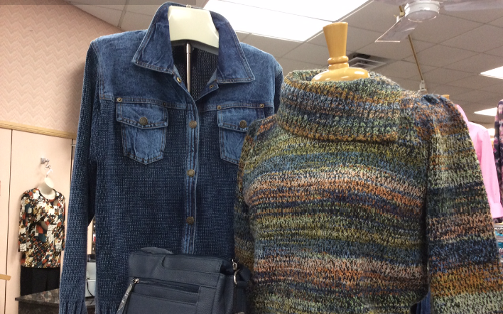 Teal blouse, ivory cardigan and navy trousers on a clothing rail
